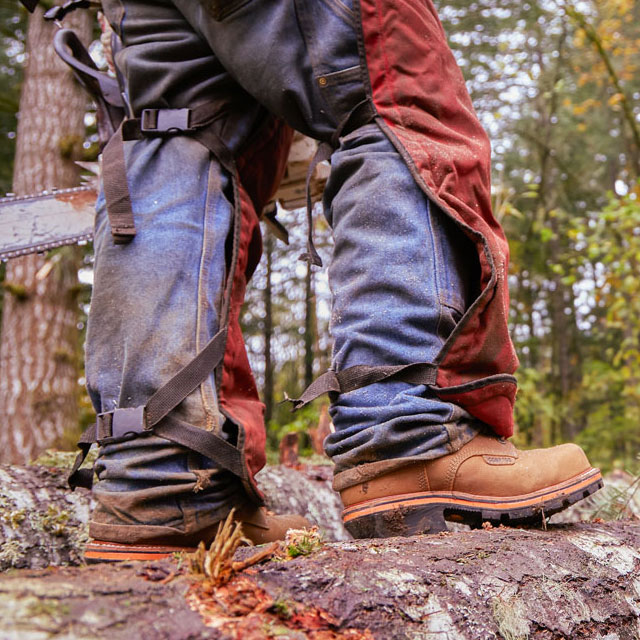 A man wearing Chippewa Super DNA work boots while standing on a log.